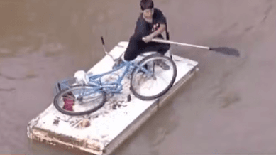 Menino improvisa jangada para levar bicicleta durante enchente no RS